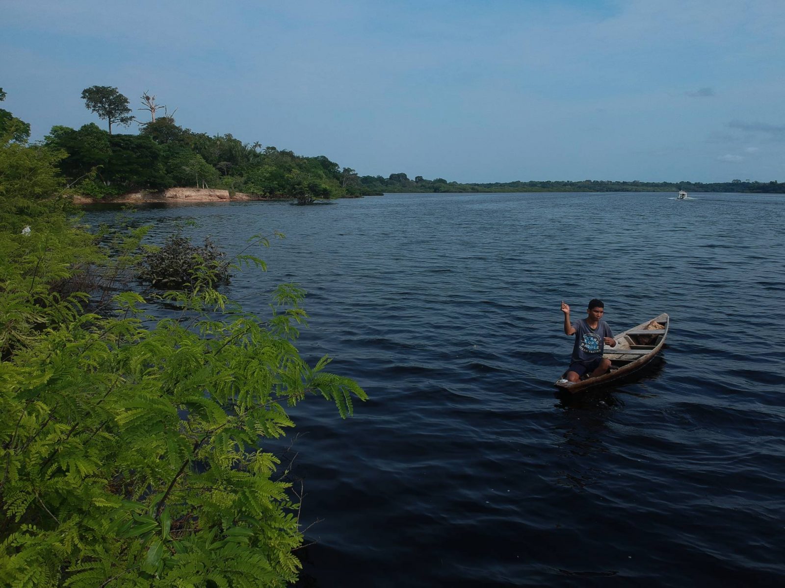 Jovem ribeirinho pescando em sua canoa.