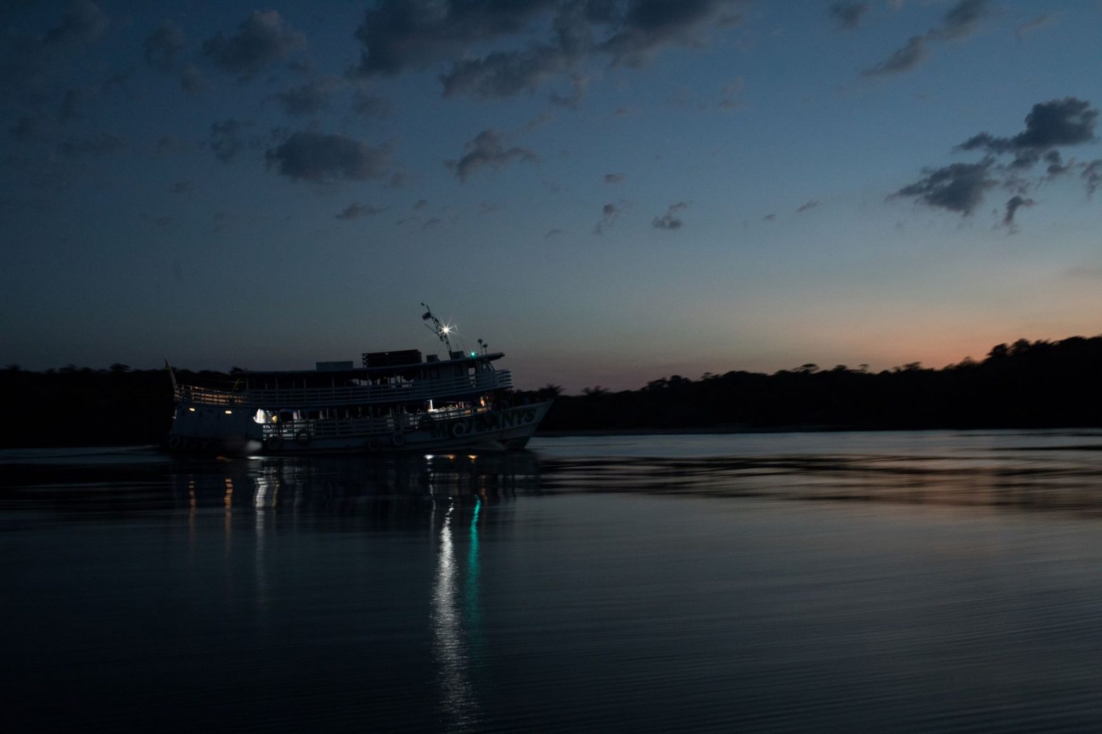 Barco navegando pelo rio ao entardecer no Amazonas.