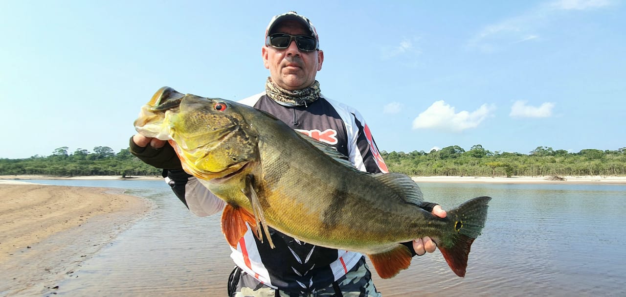 Pescador segurando tucunaré, peixe típico da Amazônia.