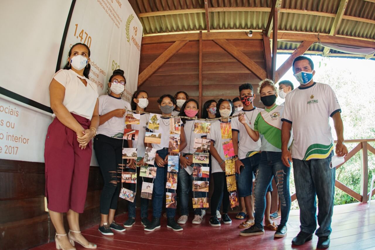 Alunos reunidos em comunidade no interior do Amazonas, realizando uma exposição de fotos.