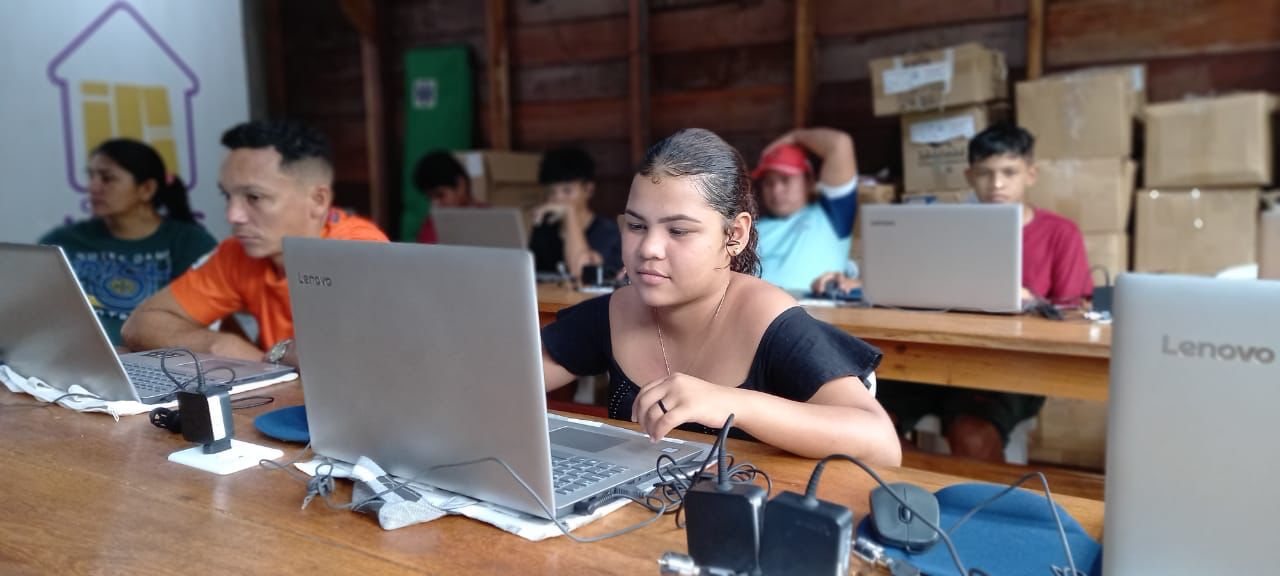 Garota mexendo em notebook, durante curso de informática realizado em comunidade no interior do Amazonas.