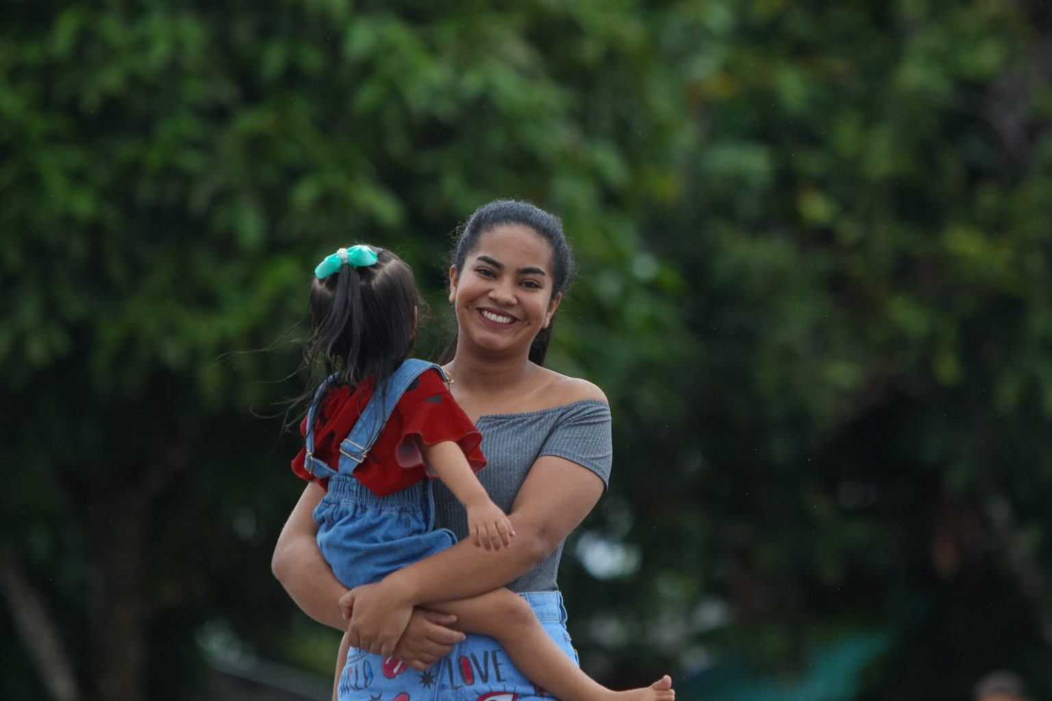 Menina sorrindo e carregando criança, caminhando em comunidade no interior do Amazonas.